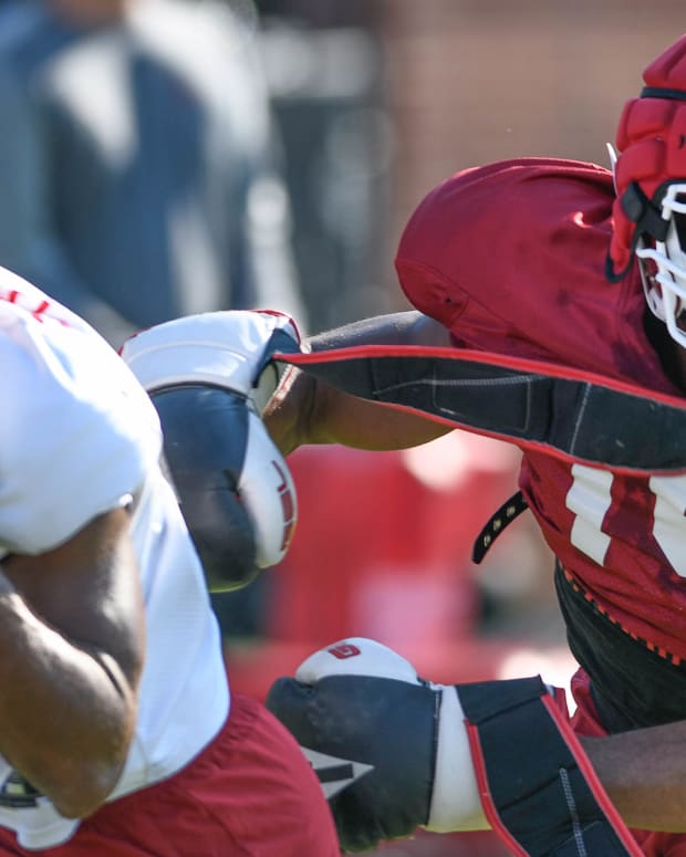 Arkansas Razorbacks defensive back Simeon Blair wears boxing gloves while covering Warren Thompson in Thursday morning's practice on the grass outdoor field at the football center in Fayetteville, Arkansas.